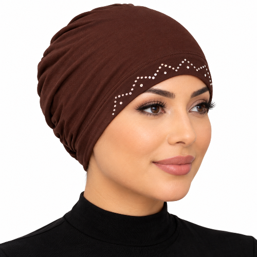 Woman wearing a brown stretch cap hijab with rhinestone zigzag trim on a white background.