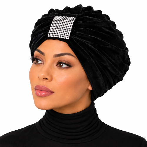 A woman wearing a black velvet turban headwrap with a square rhinestone embellishment on the front, shown against a plain white background.