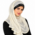 Woman wearing an ivory long wrap hijab with a black rhinestone floral detail across the forehead and matching ivory satin trim