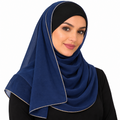 Woman wearing a navy-blue hijab scarf with thin light gold trim on a white background
