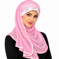 Woman wearing a light pink long wrap turban hijab with a white rhinestone headband, pink satin trim, and decorative pearl beads.