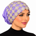 Woman modeling a purple embellished turban with gold floral lace, pearl beads, and decorative detailing on a white background.