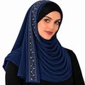 A woman wearing a navy blue hijab with a vertical decorative panel of silver rhinestones, styled over a black top against a plain white background.