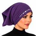 A woman wearing a purple headscarf with a row of small square mirror embellishments on the side, photographed against a plain white background.