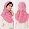 Woman modeling a pink one-piece hijab with rhinestone details, black under cap, and modest shoulder-length coverage