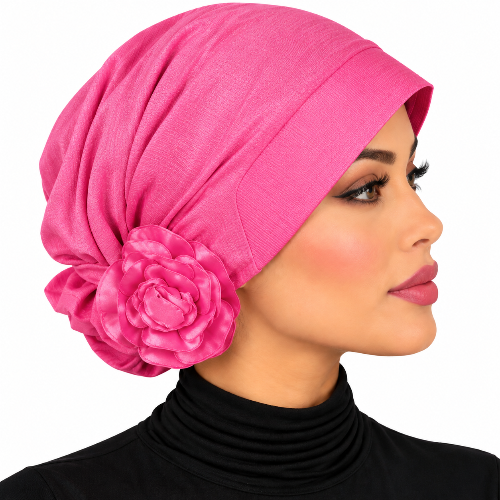 A woman in profile wearing a bright pink turban-style headscarf with a large fabric flower accent on the side, against a plain white background.
