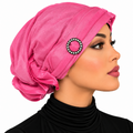 Woman wearing a pink pre-tied turban cap with a rhinestone ring detail