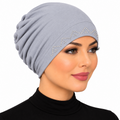 Woman wearing a light grey stretch cap hijab with silver rhinestone zigzag trim on a white background.