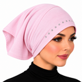 A woman wearing a light pink turban-style headscarf with small rhinestone embellishments along the front edge, shown against a plain white background.