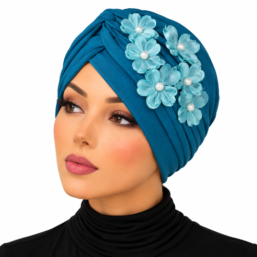 Woman wearing a teal pleated turban with light blue fabric flowers and pearl bead details